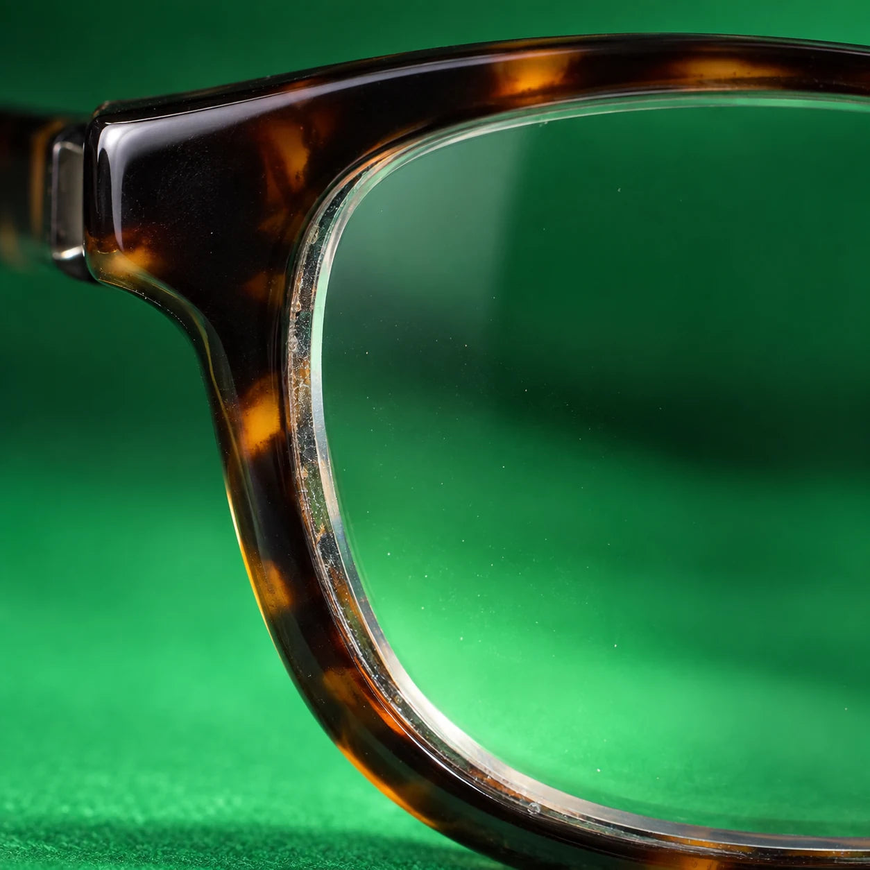 Realistic macro photograph of residue at the narrow junction between a lens edge and tortoiseshell frame